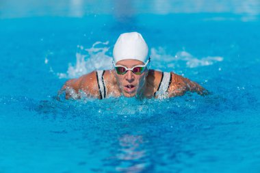 Kadın yüzücü, yunus tekniğini açık havuzda mükemmelleştirir. Yüzme, su sporu, fitness, su egzersizi, atlet eğitimi