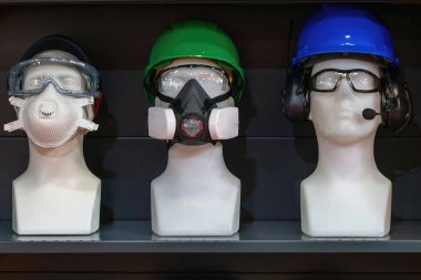 Bir mankende, sanayi ve inşaat güvenliği gösterileri için ideal kasklar, kulaklık, renkli güvenlik gözlükleri ve kaynak başlıkları da dahil olmak üzere kapsamlı güvenlik ekipmanları sergileniyor..