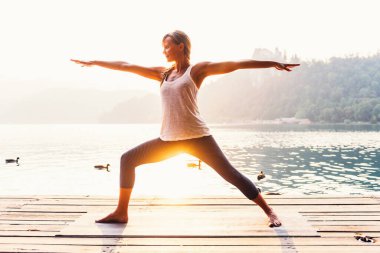 Sabah gölün kenarında yoga yapan bir kadın. 