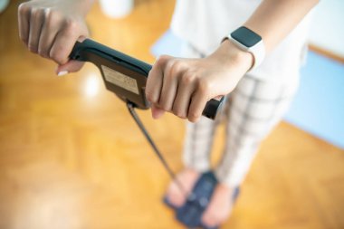 Kadın kendini vücut yağlarıyla tartıyor.