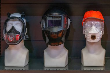 Bir mankende, sanayi ve inşaat güvenliği gösterileri için ideal kasklar, kulaklık, renkli güvenlik gözlükleri ve kaynak başlıkları da dahil olmak üzere kapsamlı güvenlik ekipmanları sergileniyor..