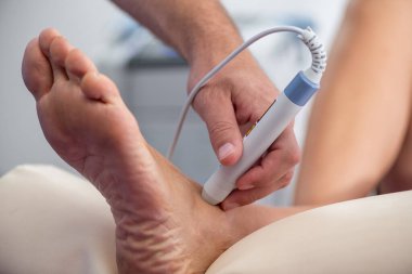 Fizyoterapist, iltihabı azaltmak ve iyileşmeyi hızlandırmak için hastaların ayak bileklerine lazer terapisi uygular. Odaklanan ışık tedavisi yaranın iyileşmesini hızlandırmayı amaçlıyor.