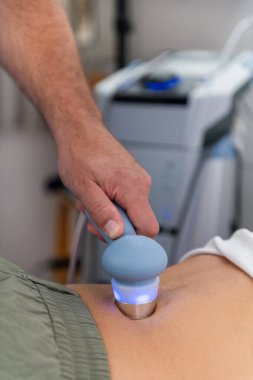Fizyoterapist hastanın belinde ultrason terapisi uygular ağrıyı azaltmak ve iyileşmeyi hızlandırmak için, profesyonel bir klinik ortamda hareket kabiliyetini ve iyileşmeyi geliştirmek için.