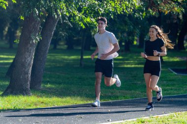 Çift parkta birlikte koşuyor, fitness 'i destekliyor, sağlıklı bir yaşam ve ortak aktif bir yaşam tarzı. Açık hava egzersizini, bağ kurmayı ve manzaralı bir park patikasının enerjisini yakalar.
