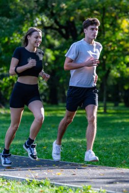 Uygun bir çift parkta birlikte koşuyor, dışarıda egzersiz yapıyor ve sağlıklı, aktif bir yaşam tarzı geliştiriyor. Zindelik, bağ kurma ve enerjik kalarak doğanın tadını çıkarmakla tanınır..