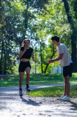 Canlı bir parkta koşuşturan, spor yapmayı kucaklayan ve aktif bir yaşam tarzı olan çift. Bu fotoğraf açık hava egzersizini, sağlığını ve doğada koşmanın keyfini vurgular..