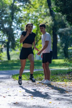 Çift parkta birlikte koşuyor, fitness 'i destekliyor, sağlıklı bir yaşam ve ortak aktif bir yaşam tarzı. Açık hava egzersizini, bağ kurmayı ve manzaralı bir park patikasının enerjisini yakalar.