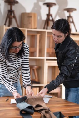 İki kadın tasarımcı yeni mobilya tasarımı için deri ve diğer malzemeler arasında seçim yapıyor..