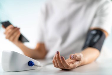 Bir kadın kan basıncını ölçer. Yenilikçi mobil sağlık çözümü, doğrudan akıllı telefona kan basıncının izlenmesine ve veri girişine olanak tanır 