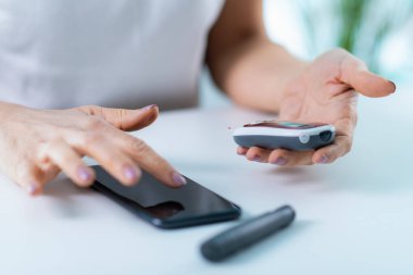 Kan şekerini taşınabilir bir glukometreyle ölçen bir kadın, diyabet yönetimi için hızlı ve doğru sonuçlar veriyor.