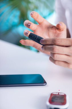 Bir kişi kan şekeri seviyesini ölçer, diyabeti kontrol etmek için temel bir görevdir.  