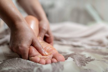 Kadınların elleri bir erkek için rahatlatıcı ayak masajı yapıyor, stresi azaltmaya odaklanıyor, kan dolaşımını hızlandırıyor ve genel olarak sağlığını arttırıyor. Rahatlatıcı ve canlandırıcı faydalarıyla bilinir..
