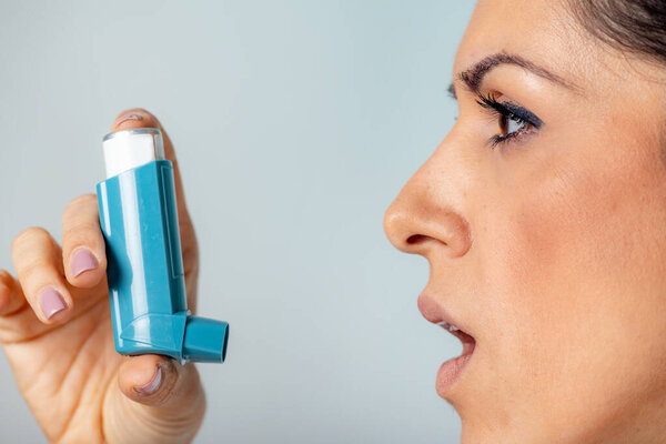 Management of asthma symptoms as a woman uses her inhaler, a vital tool for controlling respiratory distress