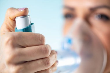 Kadın astım spreyinden nefes alarak astımı kontrol ediyor. Solunum sağlığı için çok önemli.