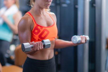 Modern bir spor salonunda kadın ağırlık kaldırıyor, fitness 'i destekliyor.