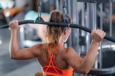 Kadın spor salonundaki bir latte egzersiz yapıyor, üst vücut gücü ve kas gelişimine odaklanıyor.