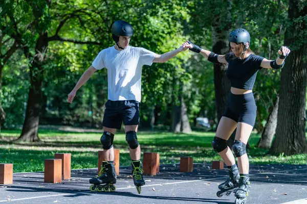 Genç çift manzaralı bir parkta birlikte paten kaymaktan hoşlanıyor. Çift yol boyunca süzülüyor, yeşilliklerle çevrili, sağlıklı kalırken eğlenceli ve aktif bir açık hava deneyimi paylaşıyor..