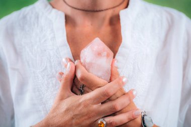 Özsaygıdeğer meditasyon konsepti. Ellerinde bir gül kuvars kristali tutarken, meditasyon yaparken, özsaygı duygusunu geliştirirken, iyi ve sevilmeye ve ait olmaya odaklanırken.