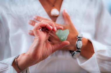 Yeşil Aventurine Kristali ile Kalp Çakra Meditasyonu yapan kadın elleri