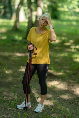 Doğanın güzelliği arasında etkin bir İskandinav yürüyüşü yapmaktan yorgun düşmüş yaşlı kadın..