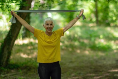 Üst düzey kadın etkili bir egzersiz için elastik direnç bandı kullanarak kasları güçlendiriyor..