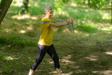 Kıdemli kadın etkili bir egzersiz için elastik direnç bandı kullanıyor..