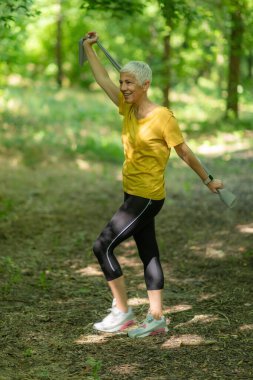 Kıdemli kadın etkili bir egzersiz için direniş bandıyla güç egzersizi yapıyor..