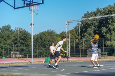 Çocuklar bir koçun liderlik ettiği açık hava basketbol antrenmanına katılıyor, teknikler deniyor ve takım çalışması yapıyorlar. Koç onlara beceri öğretiyor, eğlenceli bir ortamda disiplini ve uygunluğu teşvik ediyor.