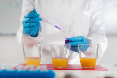 Bilim adamı, laboratuvarda kalite kontrolü için meyve suyu örneklerini test ediyor.