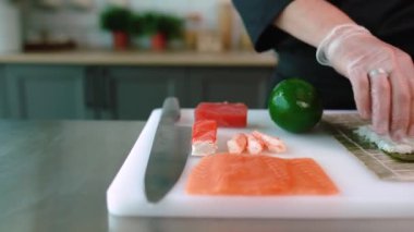 Şef suşi, rulo hazırlar. Philadelphia 'da ton balığı, avokado, yengeç ve peynirli.