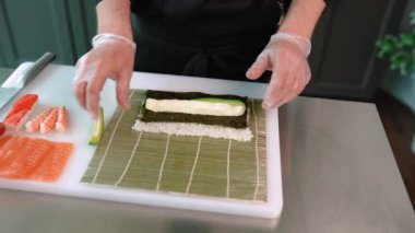 Şef suşi, rulo hazırlar. Philadelphia 'da ton balığı, avokado, yengeç ve peynirli.