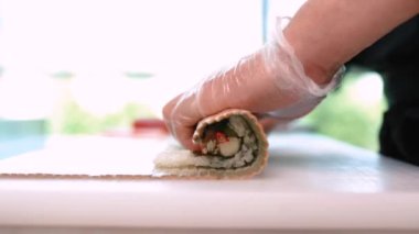 Şef suşi, rulo hazırlar. Philadelphia 'da ton balığı, avokado, yengeç ve peynirli.
