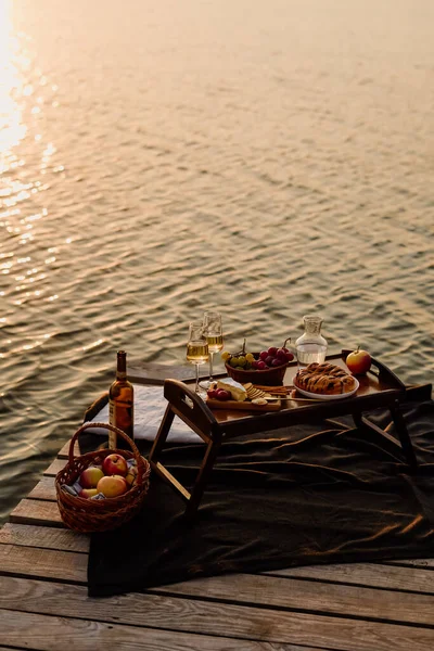 stock image Amazing sunset on the lake, white wine, fruit cake, apples, grapes, brie cheese, biscuits. Autumn aesthetic picnic.