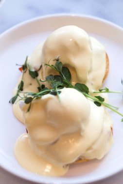 Her biri Kanada pastırması, haşlanmış yumurta ve Hollandez sosuyla kaplı iki yarım İngiliz çöreğinden oluşan sıradan bir Amerikan kahvaltısı veya brunch yemeği..