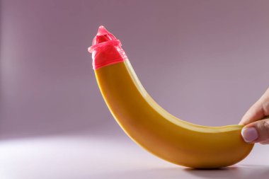 Renkli bir arka planda muz üzerinde prezervatif. Pembe prezervatif. Güvenli seks konsepti