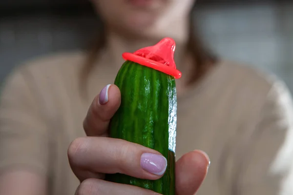 Cucumber with a condom.Woman holding a cucumber with a condom. Sex education