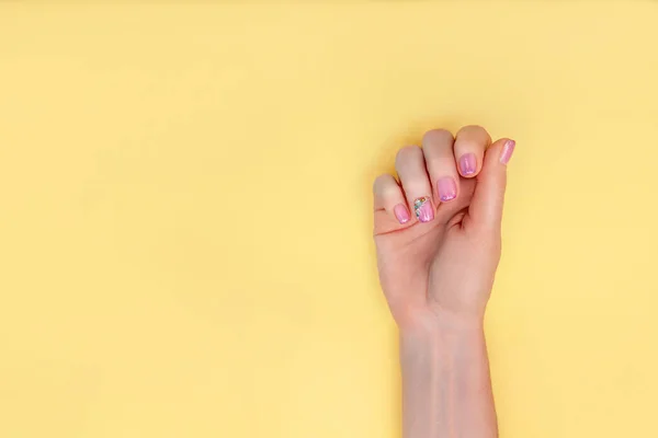 Manicure. Hands of an adult woman with a beautiful manicure on a yellow background. Gentle hands with natural manicure, clean adult skin. amazing nails