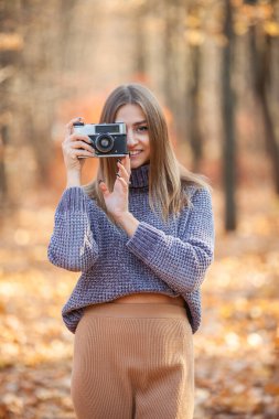 Güz Ormanı 'nda retro kameralı genç beyaz kadın.