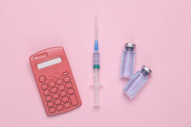 Mavi arka planda şırınga ve hesap makinesi olan aşı şişeleri. Üst Manzara. Tıbbi konsept