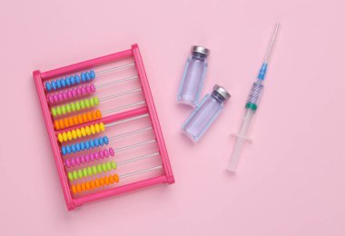 Aşı şişeli abaküs ve pembe arka planda şırınga. Üst Manzara. Tıbbi konsept