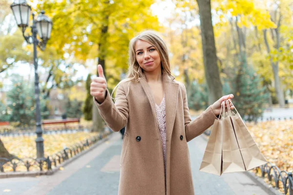 Boldog Kabátban Kezében Bevásárlótáskák Mutatja Hüvelykujját Szabadban Őszi Vásárlás Eladó — Stock Fotó