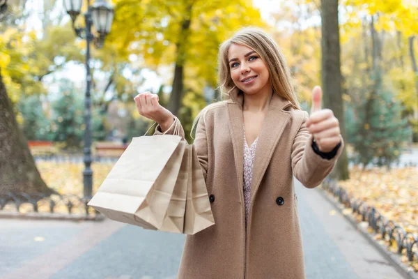 Ευτυχισμένη Γυναίκα Παλτό Που Κρατάει Τσάντες Για Ψώνια Και Δείχνει — Φωτογραφία Αρχείου