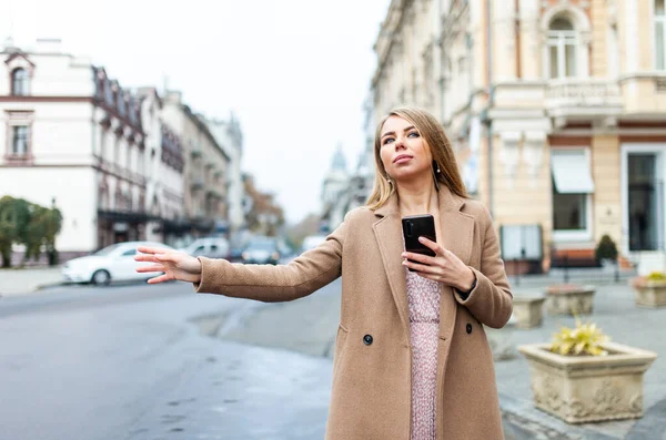 Blondýny Žena Chytání Auto Držení Smartphone Gestem Ruky Evropském Městě — Stock fotografie