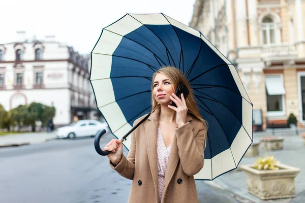 Mulher Loira Jovem Casaco Elegante Com Guarda Chuva Falando Telefone — Fotografia de Stock