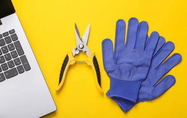 Garden pruner with work gloves and laptop on a yellow background. flat lay. top view