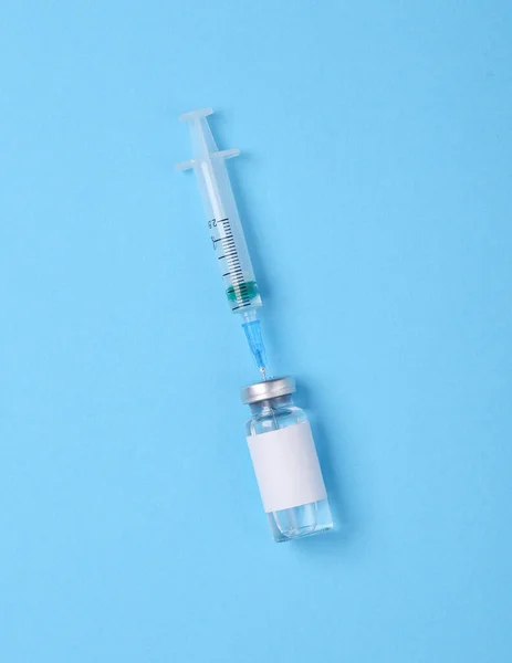青い背景にブランドと注射器のための空白のラベルを持つワクチンボトル Covid 19ワクチン接種 — ストック写真
