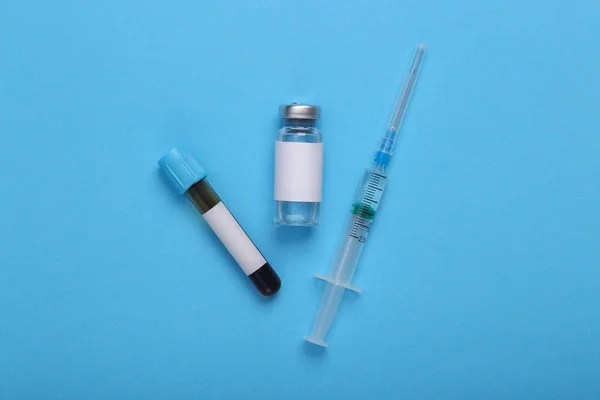 検査と予防接種 Covid 19治療 青い背景にブランドと注射器のための空白のラベルとワクチンボトルと血液検査 最上階だ — ストック写真