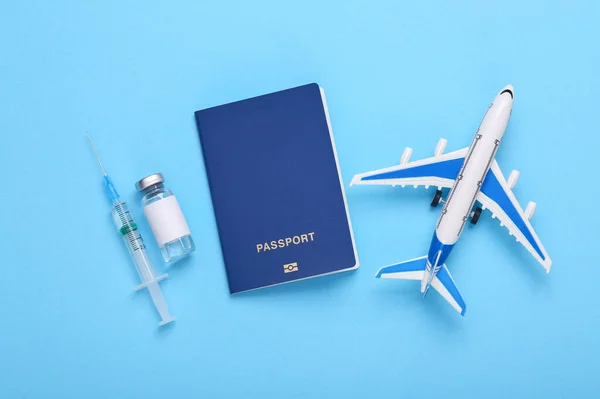 Vaccination, travel concept. Airplane with a bottle of vaccine and a syringe, passport on a blue background. Top view