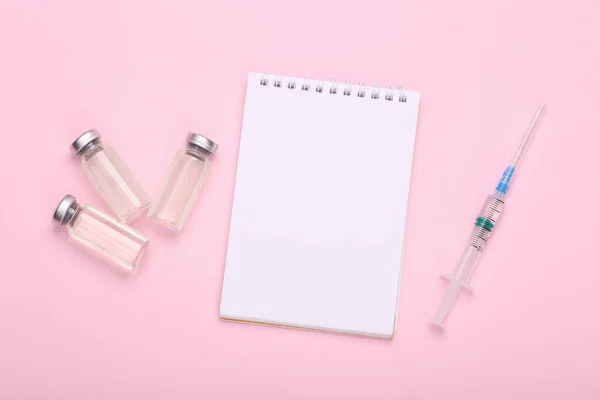 ブランドと注射器 ピンクの背景にノートブックのための空白のラベルを持つワクチンボトル コヴィド19ワクチン接種 — ストック写真