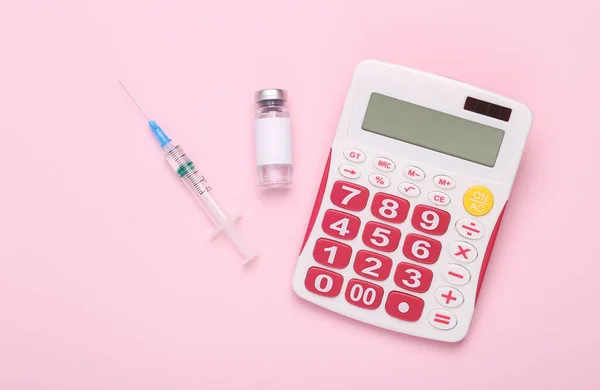 ブランドと注射器のための空白のラベルとピンクの背景に計算機とワクチンボトル — ストック写真